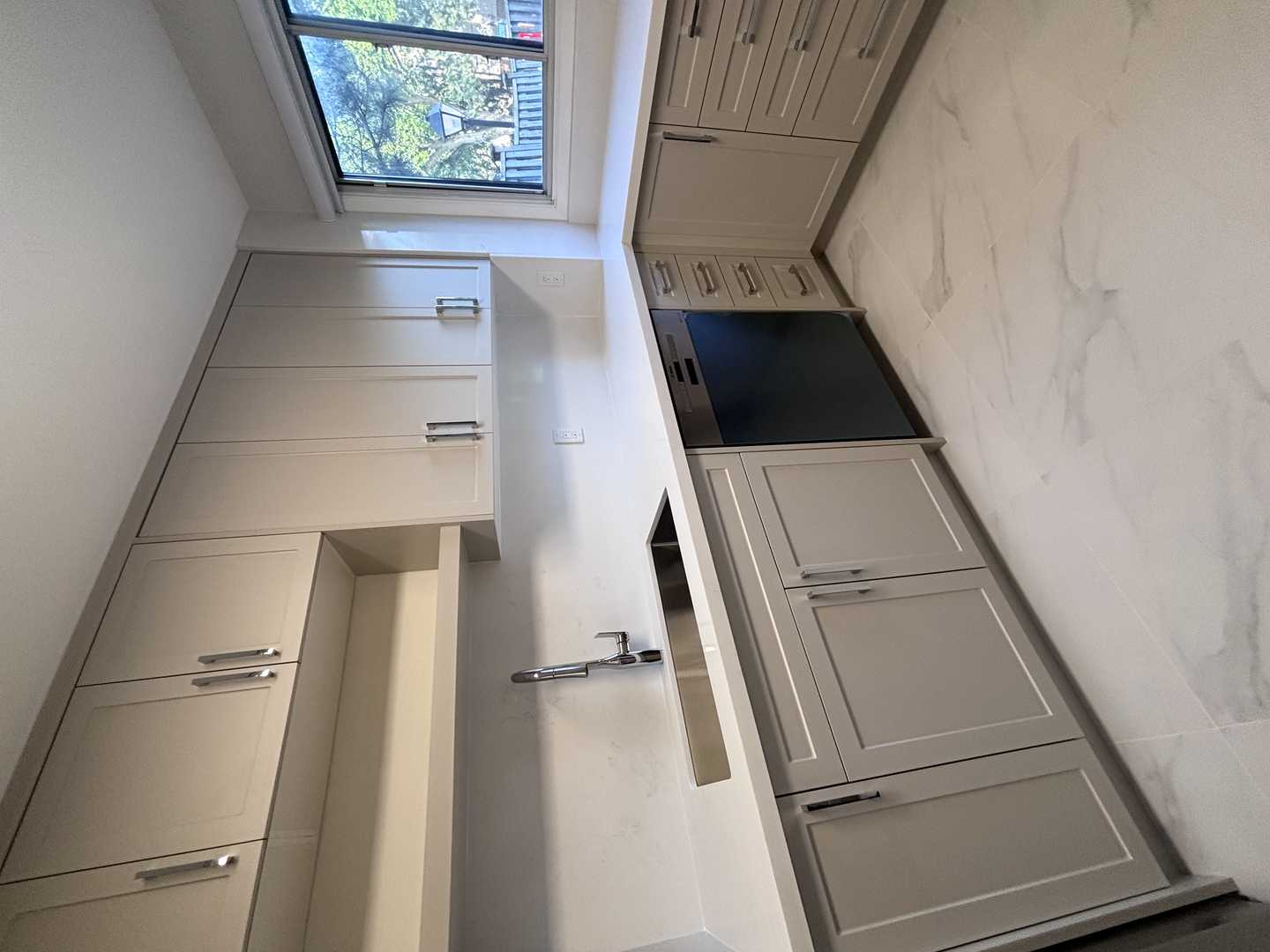 Light grey shaker kitchen cabinets w/ chrome fixtures. marble look